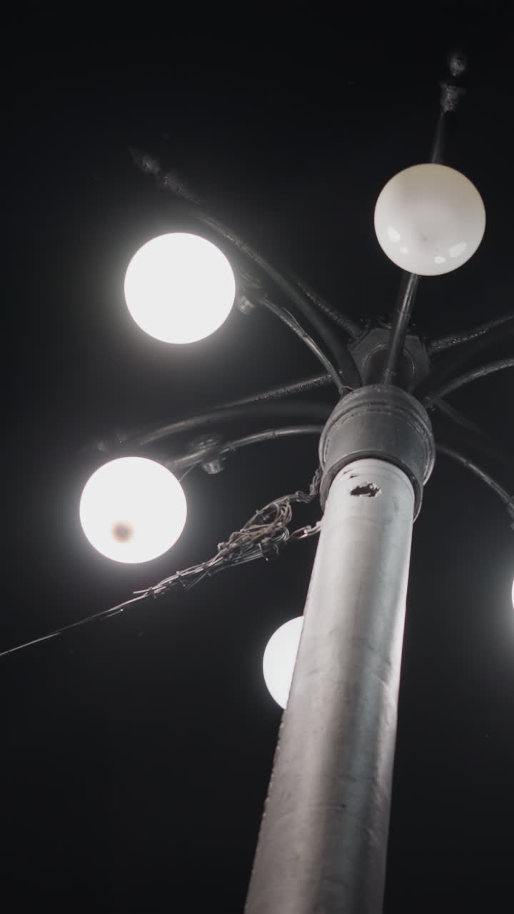 vista de cerca de un poste de farola con cinco bombillas iluminadas contra un cielo oscuro