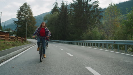 tourists enjoy biking outdoors on forest road. couple looking around mountains.