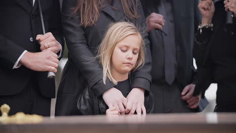 child, sad and family at funeral at graveyard