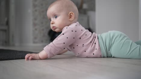 slow motion of cute caucasian blue eyed baby lying on floor, tracking shot