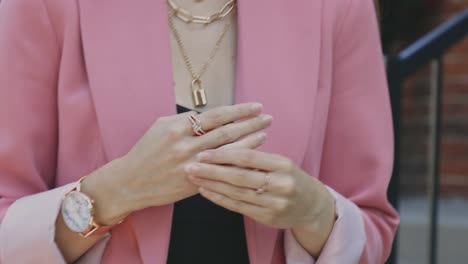 Eine-Modische-Frau-In-Schwarzem-Unterhemd-Und-Rosa-Blazer-Zeigt-Ihre-Schmuckstücke-Und-Accessoires-–-Nahaufnahme