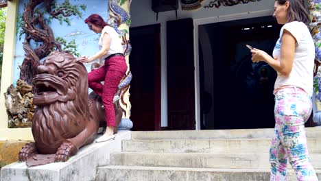 women are photographed near the statue of a lion