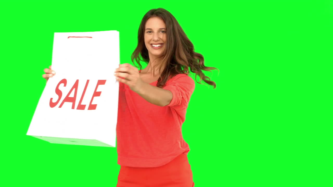 mujer girando mientras muestra una bolsa de compras en la pantalla verde