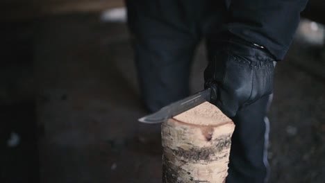 man-cutting-firewood-with-a-knife-in-winter-in-Lemmenlaakso,-Finland-shot-in120fps