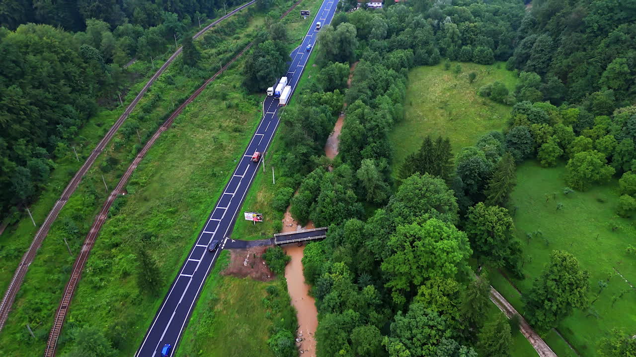 Curvy road by river and greenery. Cars travel along a winding road bordered by greenery and a river, showcasing the natural beauty of the area