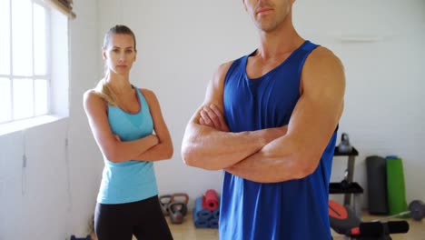 hombre y mujer con las manos cruzadas de pie en el gimnasio 4k