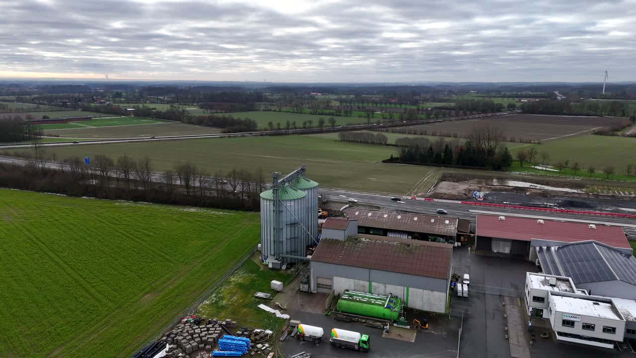 Silo Storage of agricultural factory in german Town. Traffic on highway and intersection in german. Rural countryside landscape. Wide shot.