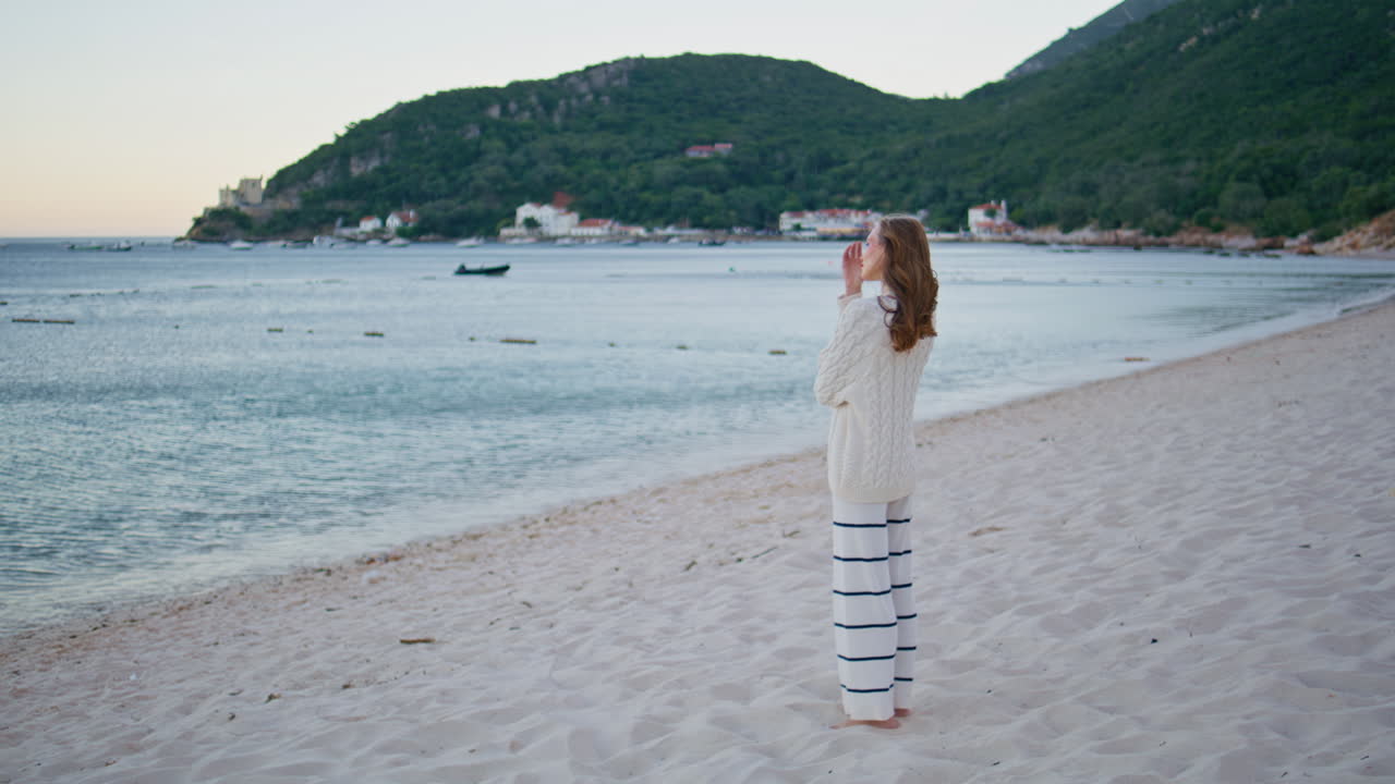 Dreamy woman looking ocean horizon on windy beach. Romantic female tourist