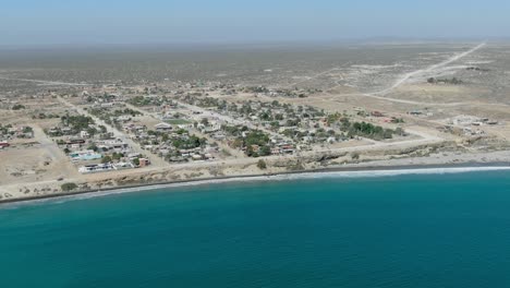 aerial view descending shot, scenic view of the city of san juanico in california sur, mexico, cars moving along the highway near the coastline on a bright sunny day