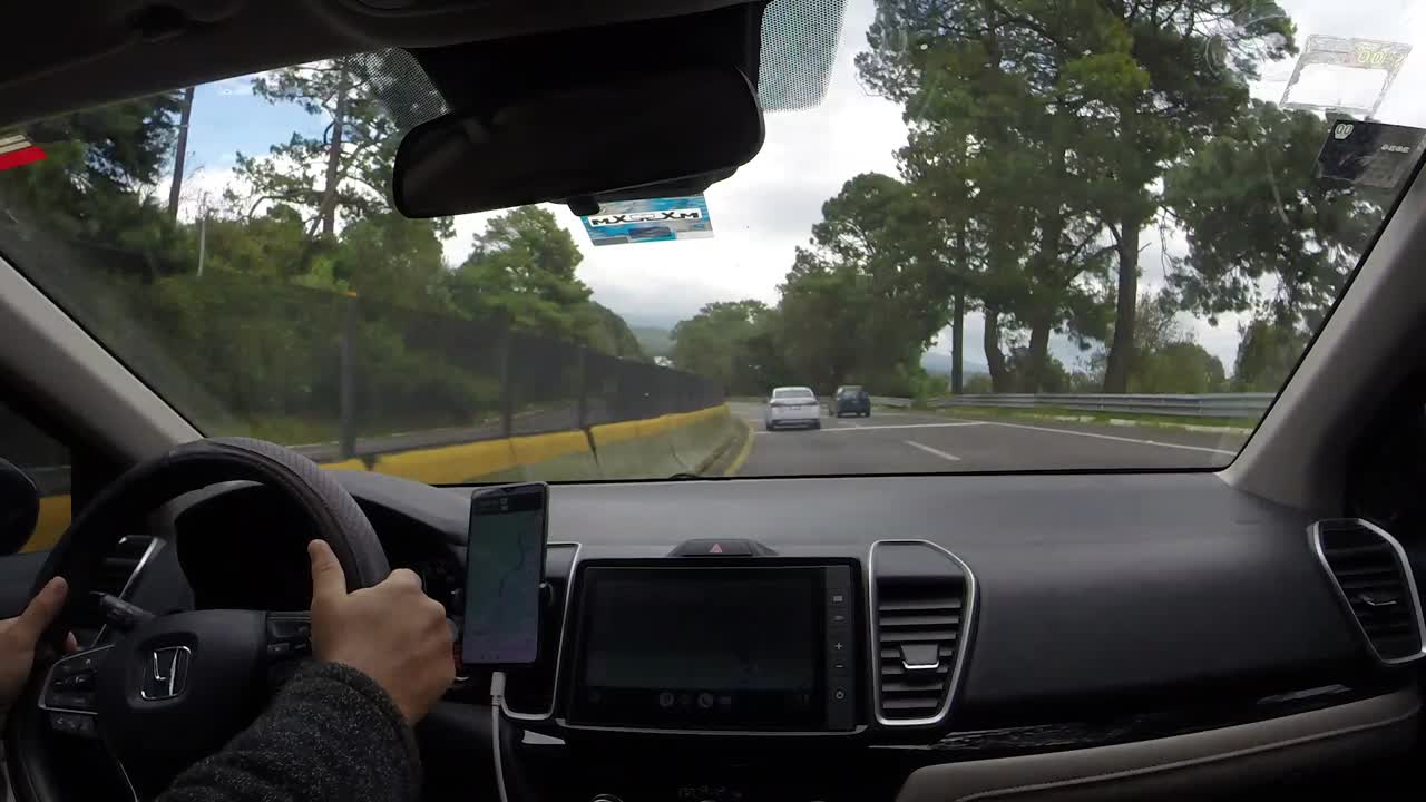 Driving on the Cuernavaca highway in Morelos, Mexico, surrounded by lush green trees, timelapse view