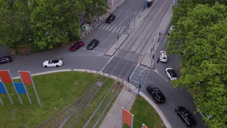 aerial view of black cars in a roundabout with tram crossing