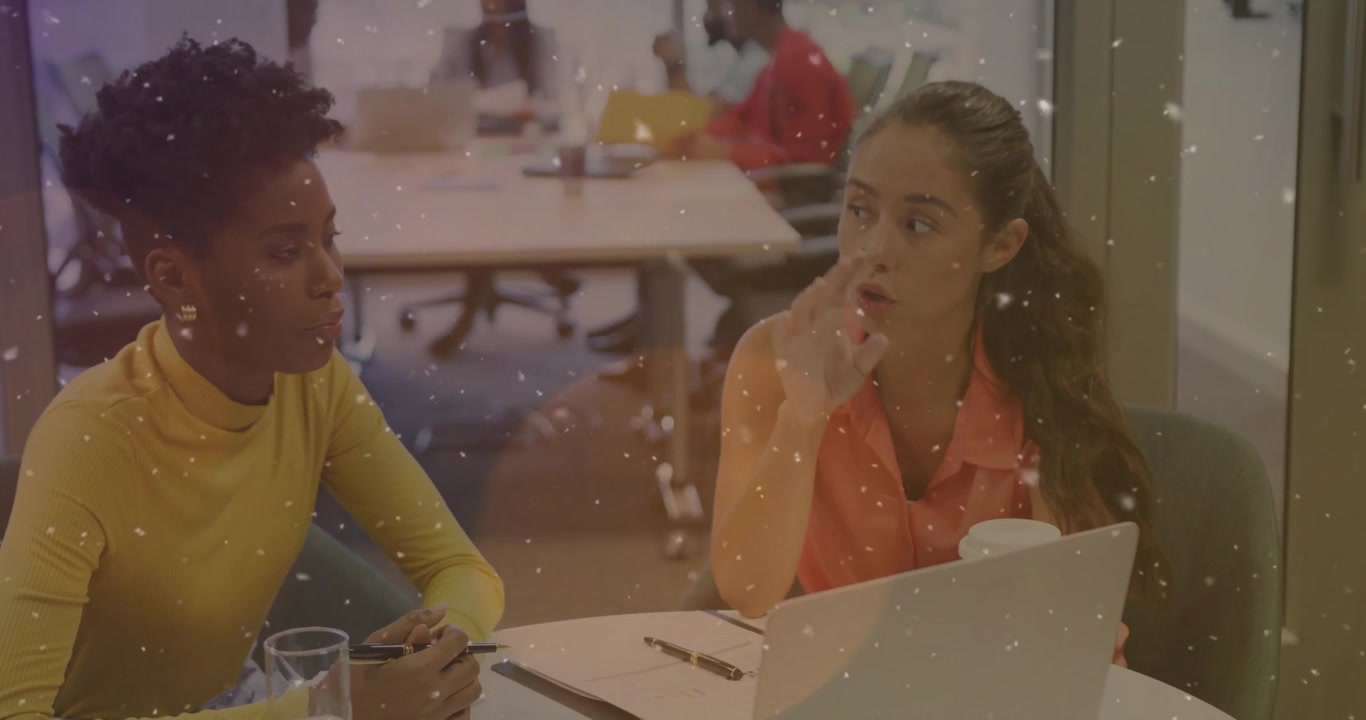 Mulher de laranja apontando para a tela do laptop e guiando colega através de anotações em reunião de negócios.