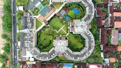 Tropical-resort-hotels-near-oceanside-in-Bali,-aerial-top-down-view