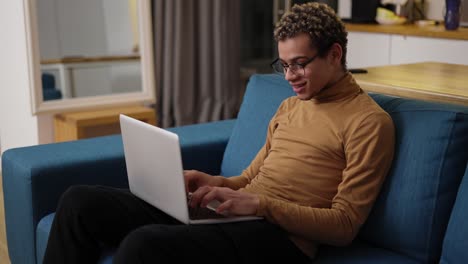 joven usando una computadora portátil en el sofá