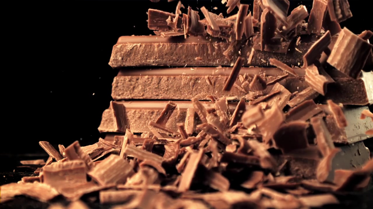 Scaglie di cioccolato che cadono su una pila di tavolette di cioccolato