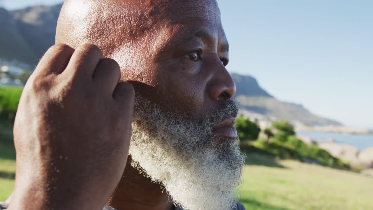 hombre afroamericano senior ejercitando poniendo auriculares en
