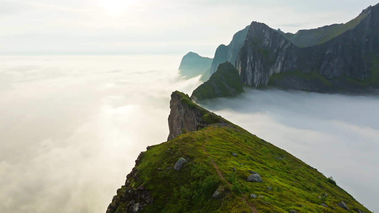 Drone flight over arctic Senja Norway ridge toward foggy pointed mountains
