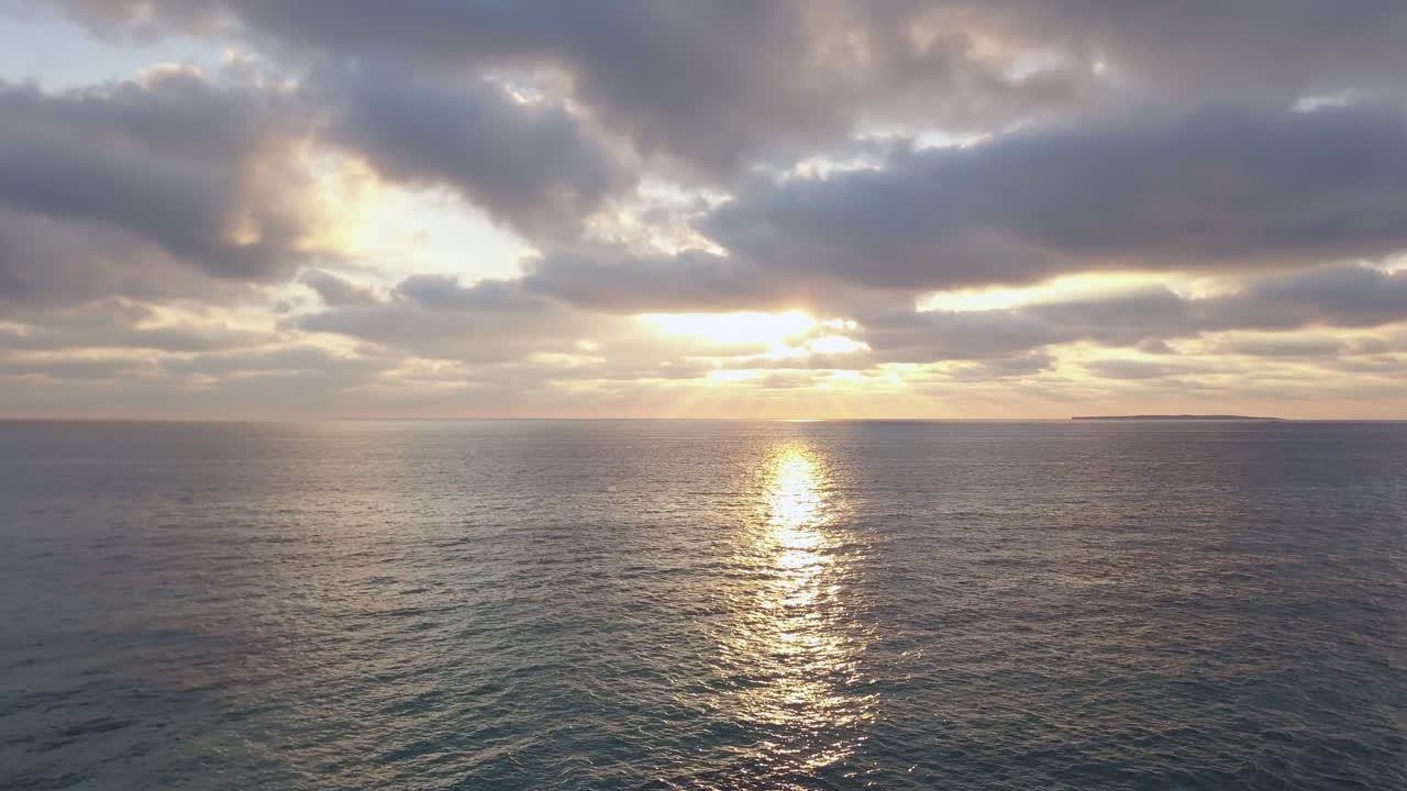 잔잔한 바다 위의 구름을 통해 엿보는 태양 광선