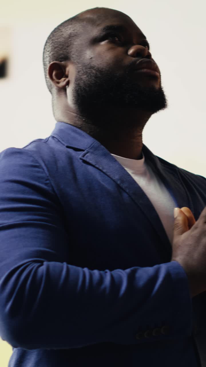 Uomo afroamericano che prega con le mani giunte guardando verso l'alto