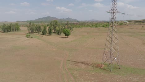 aerial - descending shot of vast landscape by massive power line in nigeria