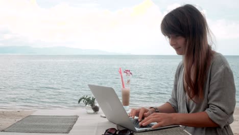 young woman works on laptop in outdoor cafe, moving camera, stabilizer shot