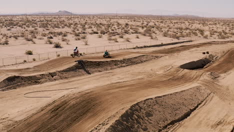 volando sobre la pista de carreras de tierra mientras los pilotos de motocross corren en cámara lenta, seguimiento aéreo