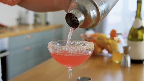 Woman-with-Shaker-Pouring-Cocktail-Drink-to-Glass.drinks-and-people-concept--young-woman-with-shaker-pouring-cocktail-to-glass-at-home-kitchen