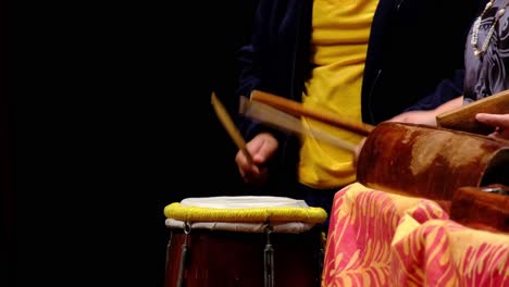 Close-of-the-children's-hand-playing-pacific-island-drum-with-the-islander-at-a-festival-on-stage-in-Auckland,-New-Zealand