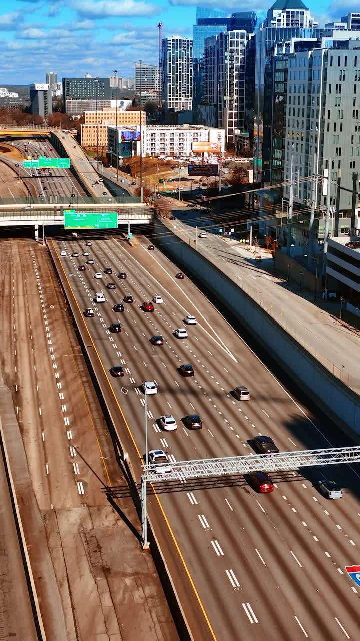 Multiple vehicles moving by the wide roads of Atlanta, Georgia, USA. Top view on city downtown on sunny daytime. Vertical video