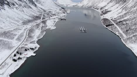 Drohnenansicht-In-Der-Gegend-Von-Tromso-Im-Winter,-Die-über-Einen-Fjord-Fliegt,-Der-Von-Weißen-Bergen-In-Norwegen-Umgeben-Ist