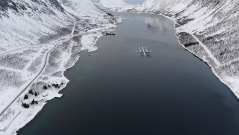 vista del avión no tripulado en el área de tromso en invierno volando sobre un fiordo rodeado de montañas blancas en noruega