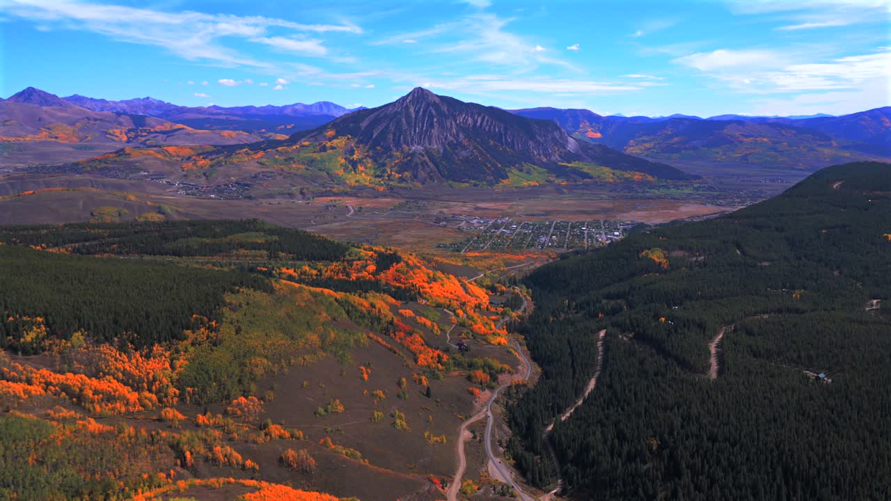 Mount Crested Butte Colorado drone aerial fall Elk Range Rocky Mountains Crested Butte ski resort town autumn Quaking colorful Aspen Trees blue sky clouds Coal Creek Kebler Pass forward pan up motion