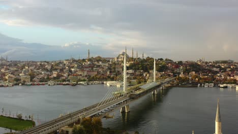 Aerial-drone-of-a-cloudy-sunrise-morning-in-Istanbul-Turkey-as-seagulls-fly-across-Halic-Metro-Bridge-and-the-Bosphorus-River