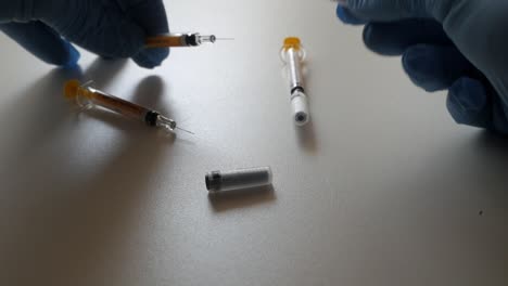syringes being handled with gloved hands, focusing on their preparation and usage
