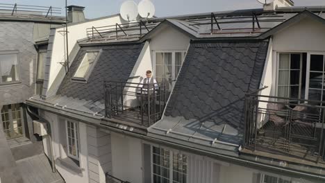 man sitting on a rooftop balcony with a laptop