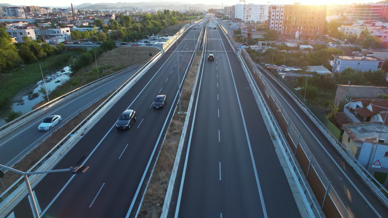 City ring road highway and river through suburban buildings in Tirana at twilight with moving traffic