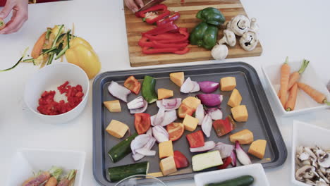 una feliz pareja de lesbianas caucásicas preparando comida en una cocina soleada