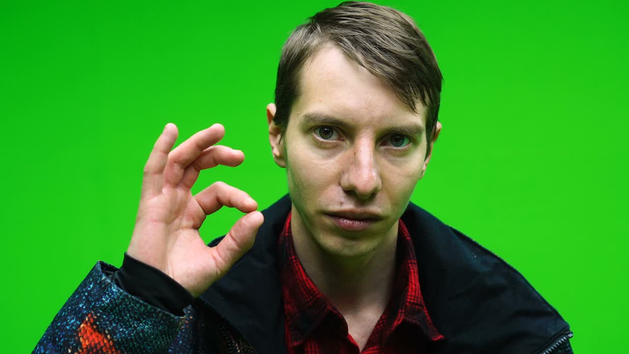 캐주얼 옷을 입은 젊은 남자가 녹색 스크린 배경에 ok 신호 손을 보여줍니다.