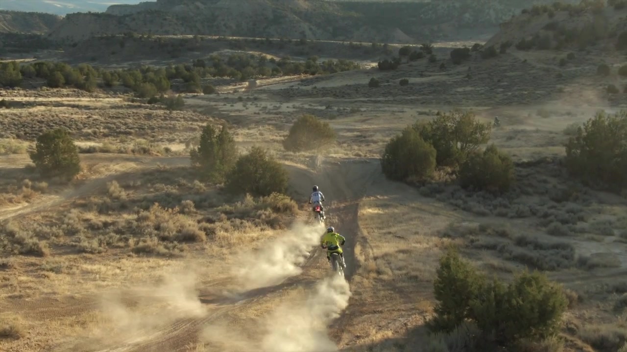 Drones aéreos seguem duas motos de trilha no deserto do Colorado no final da tarde.