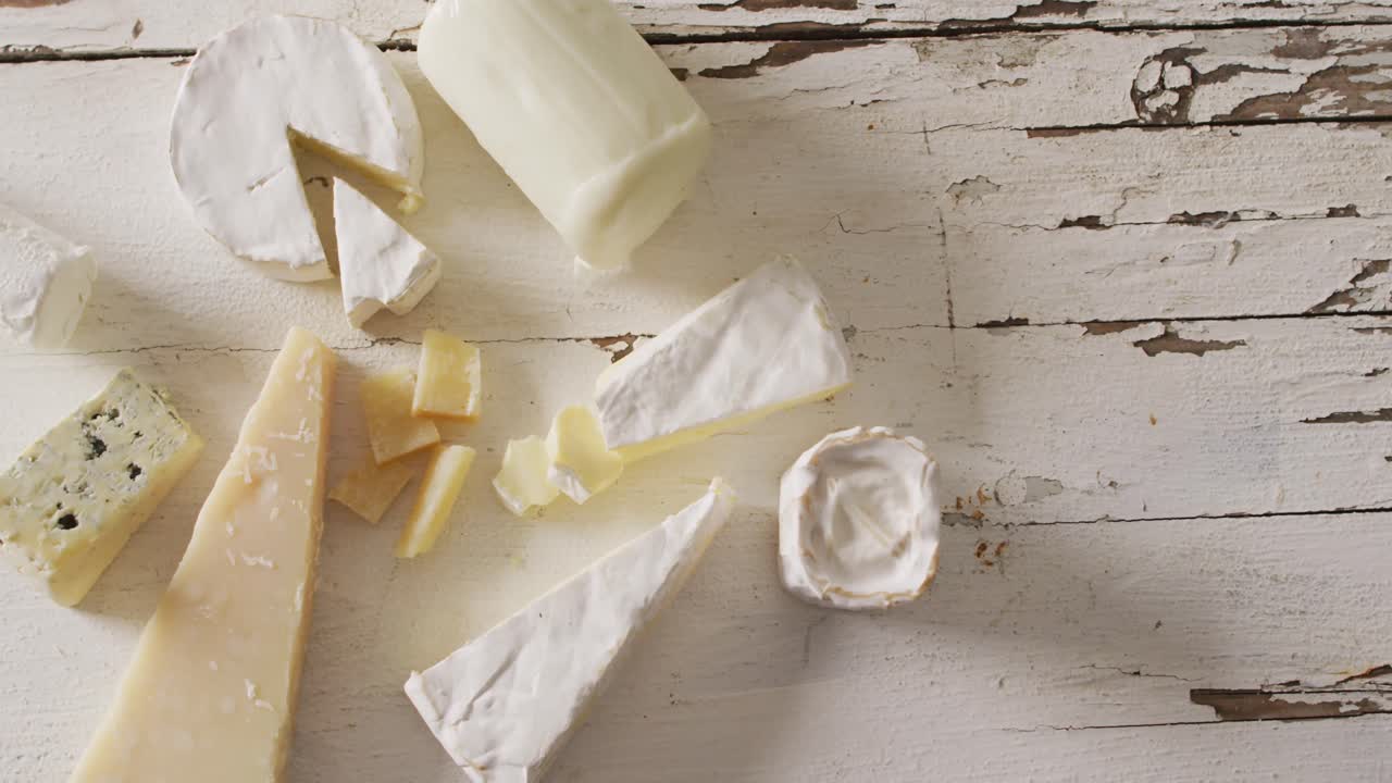 video de quesos duros y blandos variados en una mesa de madera blanca rústica, con espacio para copiar