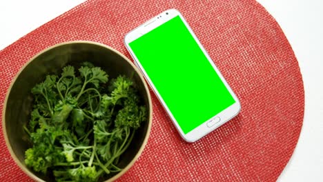 corianders in bowl with mobile phone on place mat 4k