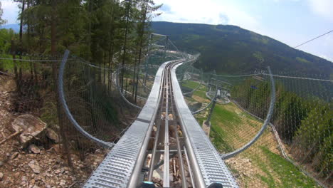 pov gopro shot of a man riding on an elevated fenced outdoor roller coaster in the mountains of dolní morava, czech republic, descending down in a spiralling loop