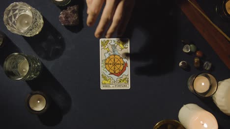 overhead shot of person giving tarot card reading laying down the wheel of fortune card on table