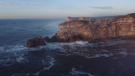 aerial view of lighthouse in front of nazare in portugal during sunset