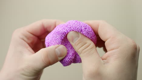 colorful purple floam being squished between fingers, focusing on the texture and sensory appeal