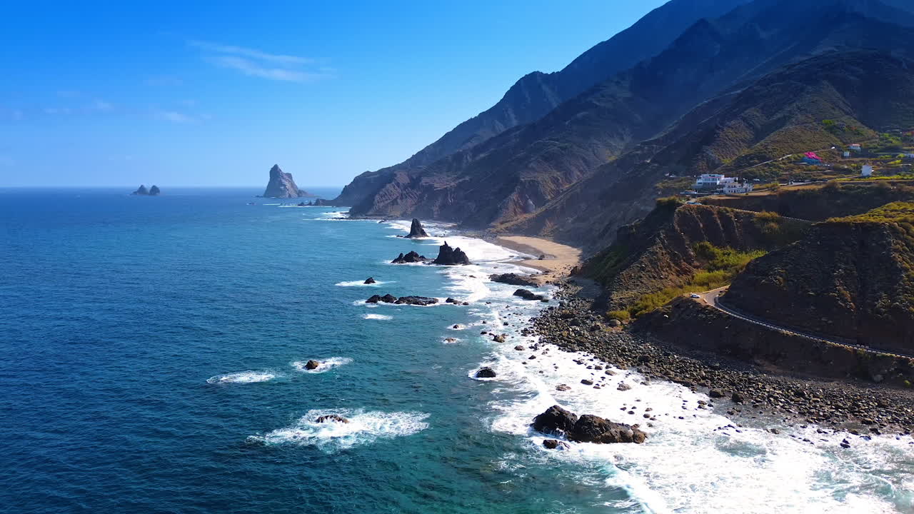 Le onde dell'Oceano Atlantico si infrangono sulla costa rocciosa di Tenerife, nelle Isole Canarie, in Spagna. Filmato delle nude rocce dell'isola con alcune case.