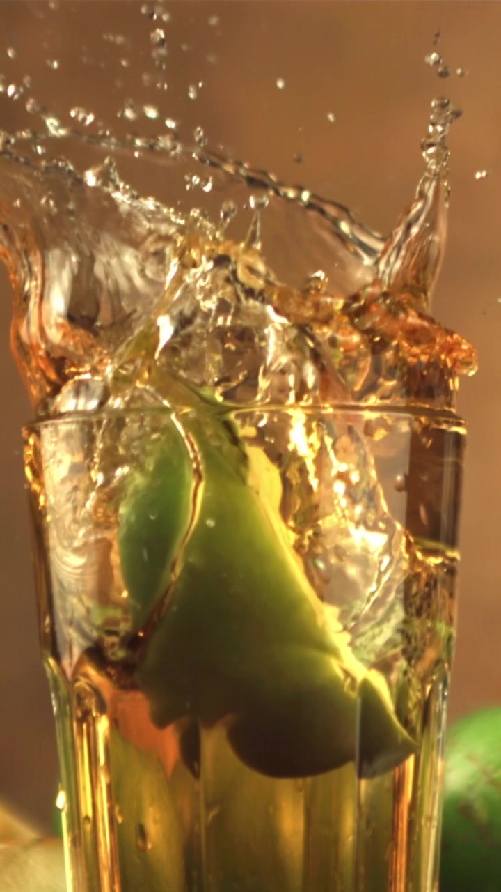 Fetta di mela verde che cade in un bicchiere di succo con uno schizzo