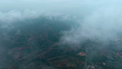dolly en vista aérea de un vuelo a través de las nubes sobre exuberantes montañas cubiertas de nubes