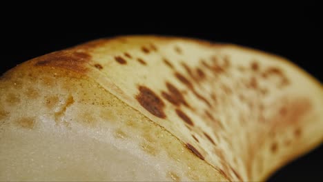 Cinematic-smooth-pan-across-the-peel-of-a-ripe-banana,-captured-against-a-black-background-under-studio-lighting