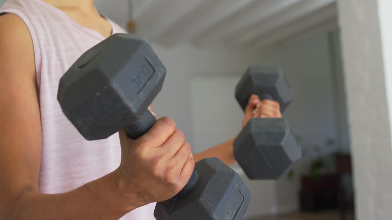 Mujer cambiando el agarre y haciendo curl con mancuernas hexagonales de 3 kg en una sesión de fitness en casa, con la cámara subiendo.